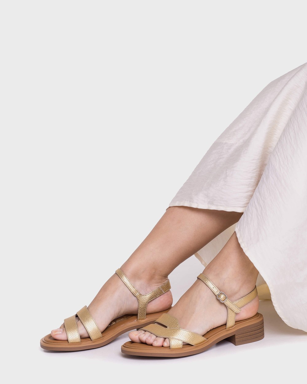 Sandalias doradas elegantes combinadas con pantalón blanco para eventos de verano